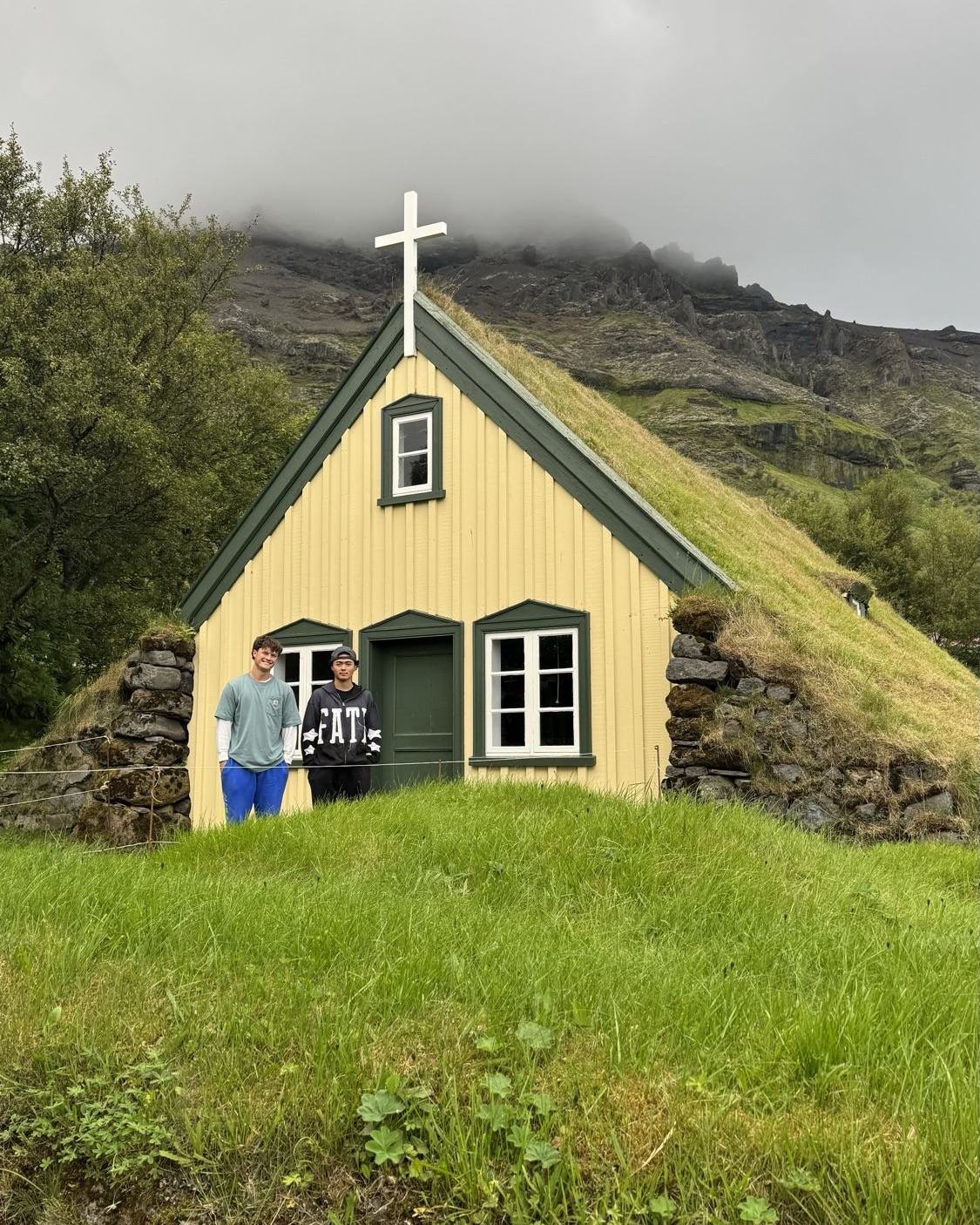 A turf roofed church under an Icelandic mountain